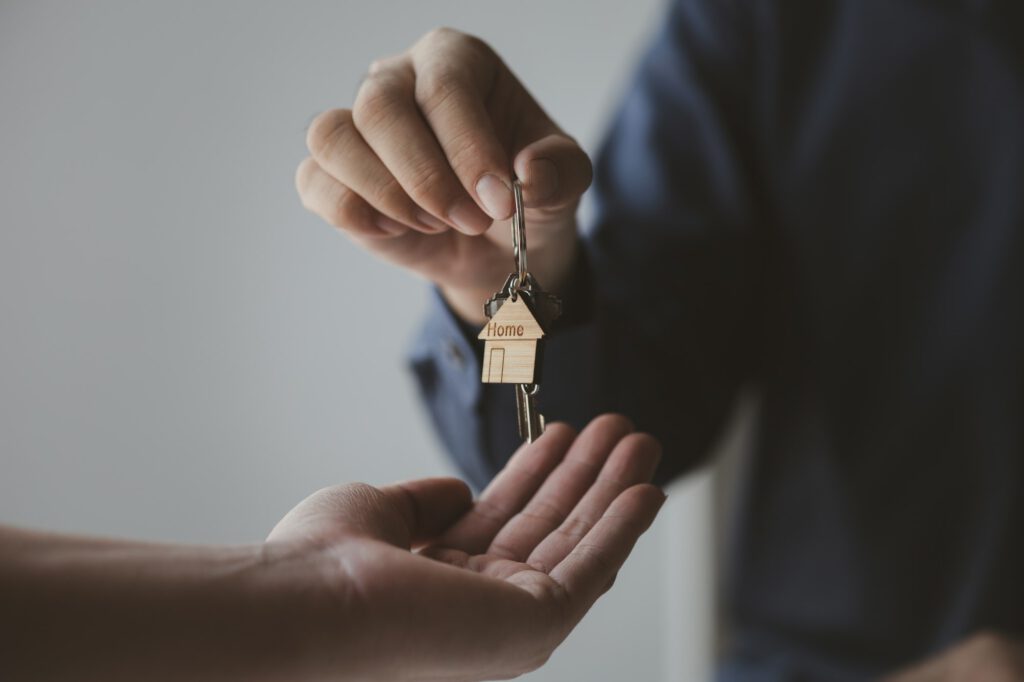 A home rental company employee is handing the house keys to a customer who has agreed to sign a rent