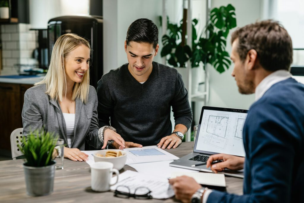 Happy couple consulting with real estate agent about housing plans on a meeting.