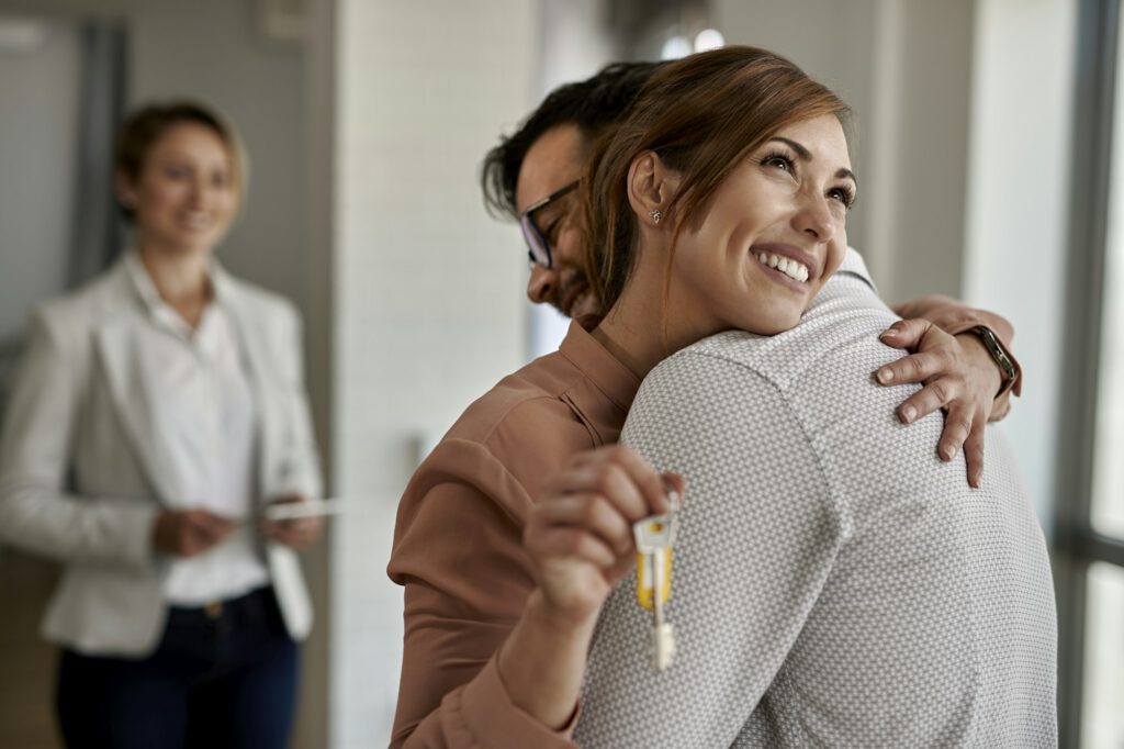 Young happy couple embracing after buying their new home.