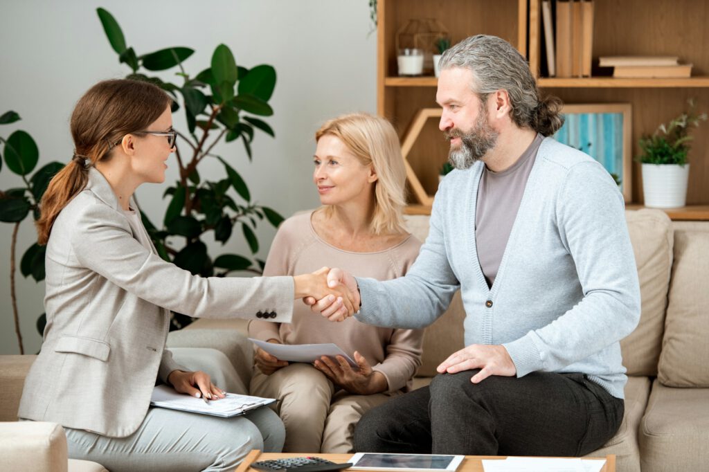 Young real estate agent congratulating mature couple with buying new house